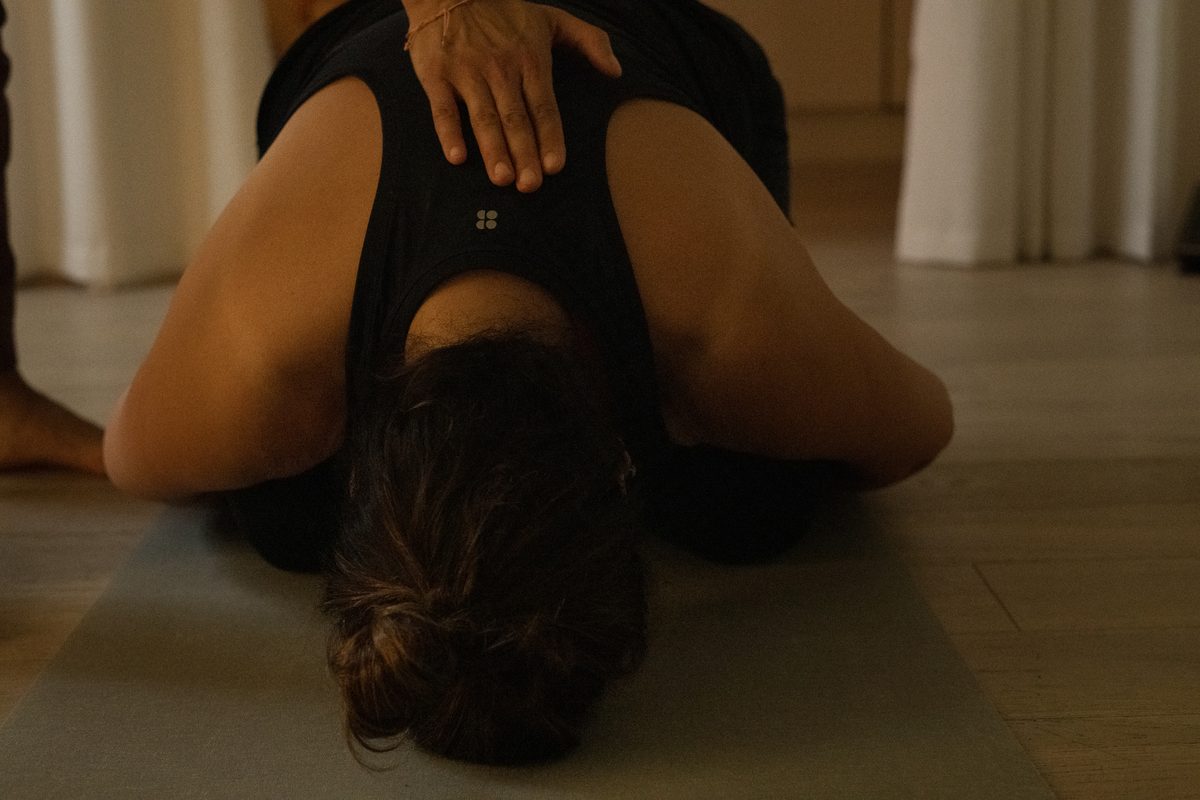 A hand resting on the sacrum in a supported forward rest